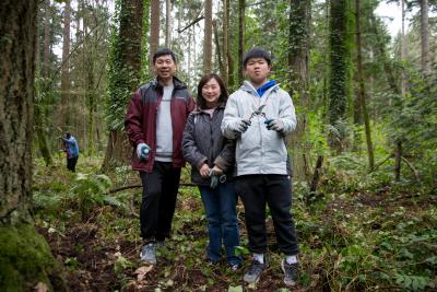 Family poses with tools in front of a forest of trees.