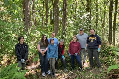 Group of volunteers posing in front of a sunny forest.