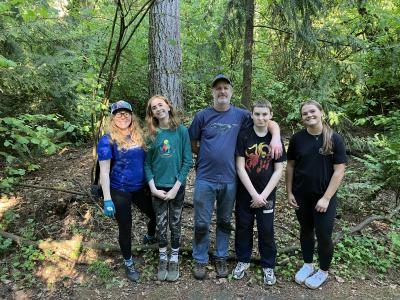 A group of volunteers posing in front of a forest. 