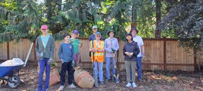 Volunteers posing on a trail in front of a fence. 