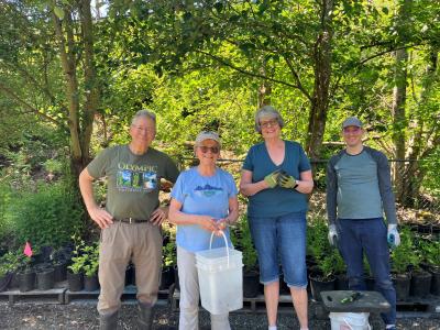 Volunteers posing in front of potted plants.