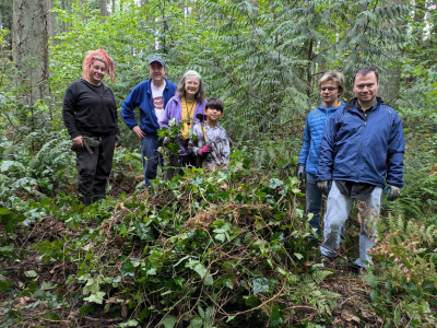 A group of volunteers standing in front of a pile of ivy. 