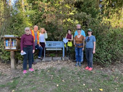 A group of volunteers posing in front of a "Wildwood Park" wooden sign.