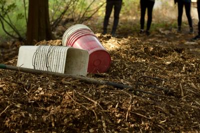 A pile of mulch with some buckets laying on top of it.