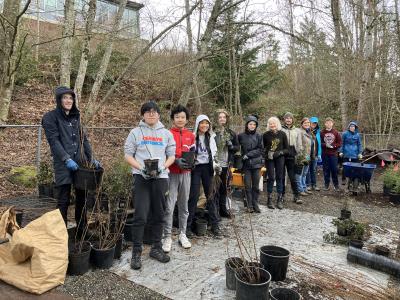 A group of volunteers posing with nursery pots. 