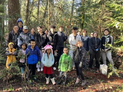 A group of volunteers posing on a sunny day in a forest. 