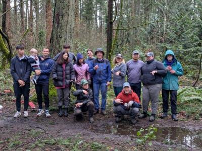 A group of four volunteers, posing in front of a forest, on a rainy day.