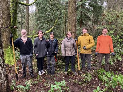 A small group of volunteers posing on a rainy day in the forest. 