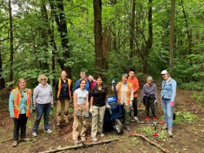 A large group of volunteers posing in front of a forest on a cloudy day. 
