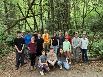 A large group of volunteers posing in the forest on a wet and cloudy day. 