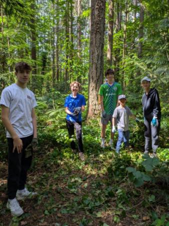 A group of volunteers posing in the the forest in front of piles of ivy.