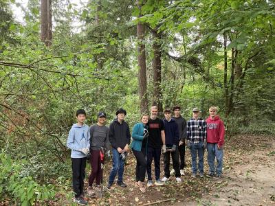 A group of volunteers posing alongside a trail in front of a forest. 