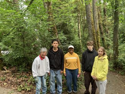 A small group of volunteers, posing in front of a a forest. 