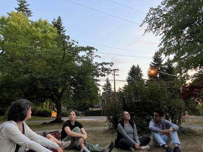 Four people sitting in the park, looking up at the sky.
