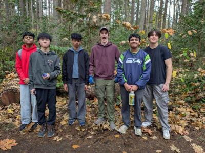 A group of volunteering posing in the park on a rainy day.