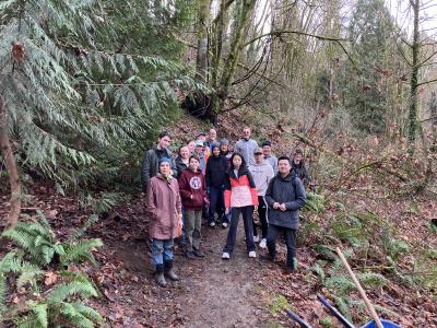 A group of volunteers posing along a trail on a cloudy day. 