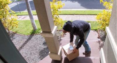 A photo of a person taking a package from a front porch of a house