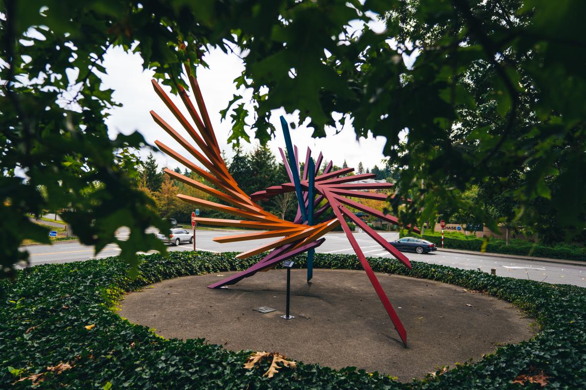 A dynamic, multicolored geometric sculpture evokes a great bird's expansive wings.