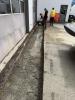 Asphalt removed at high-bay doors, compacting backfill in progress.